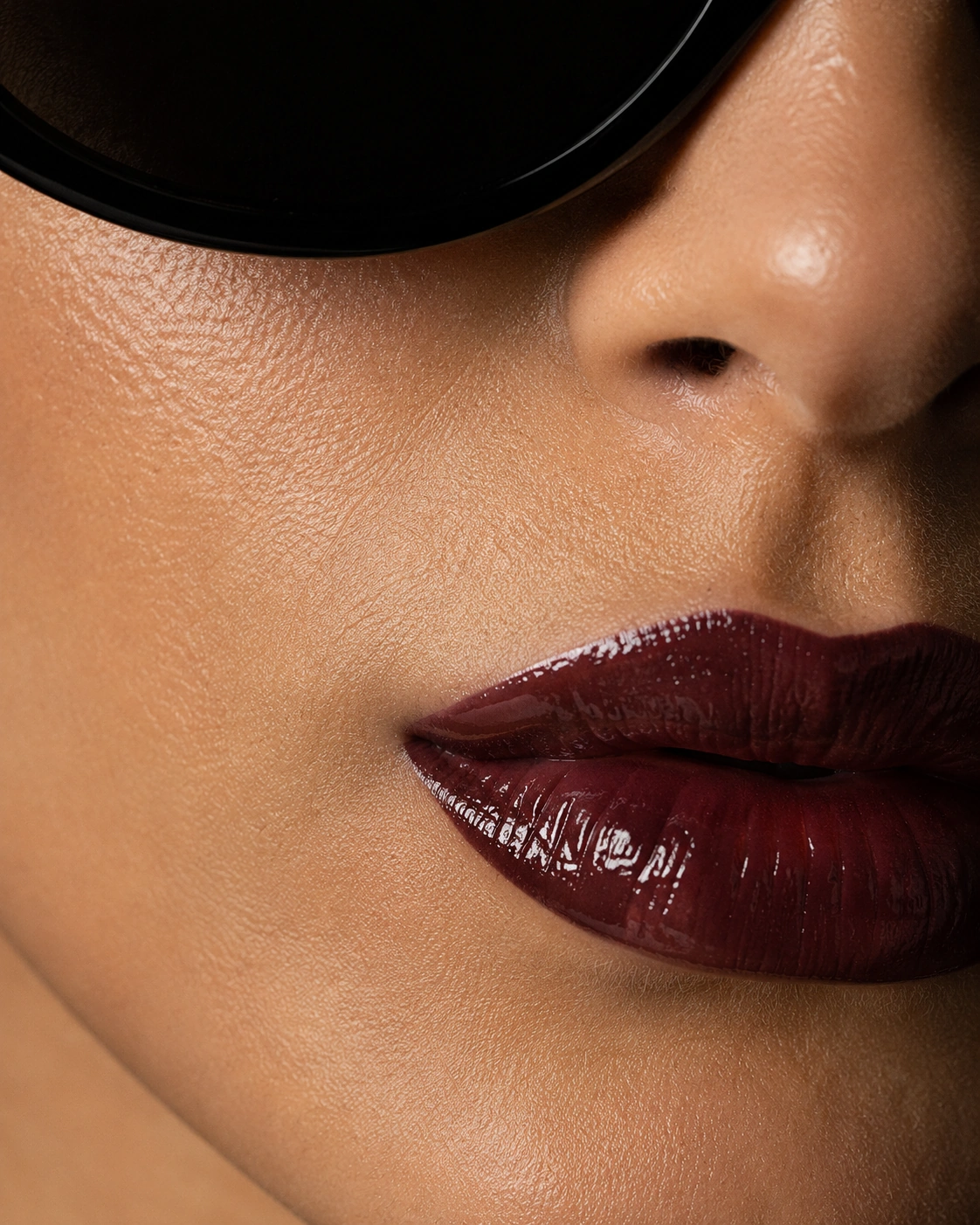Close detail of lips and the edge of black sunglasses